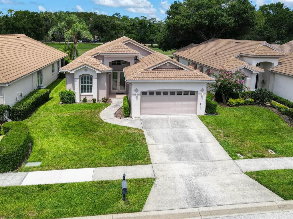 An aerial view of a single-story suburban house with a tiled roof and concrete driveway — 3944 SILK OAK LANE, PALM HARBOR, FL