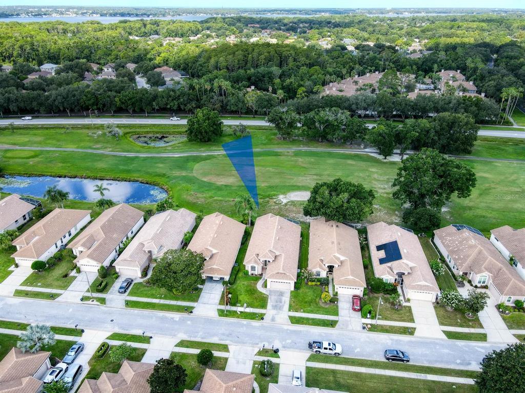An aerial view shows a row of suburban houses bordering a golf course and pond — 3944 SILK OAK LANE, PALM HARBOR, FL