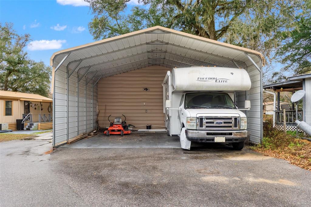 A metal carport shelters a white motorhome and a red riding lawn mower — 7154 CO RD 651, BUSHNELL, FL
