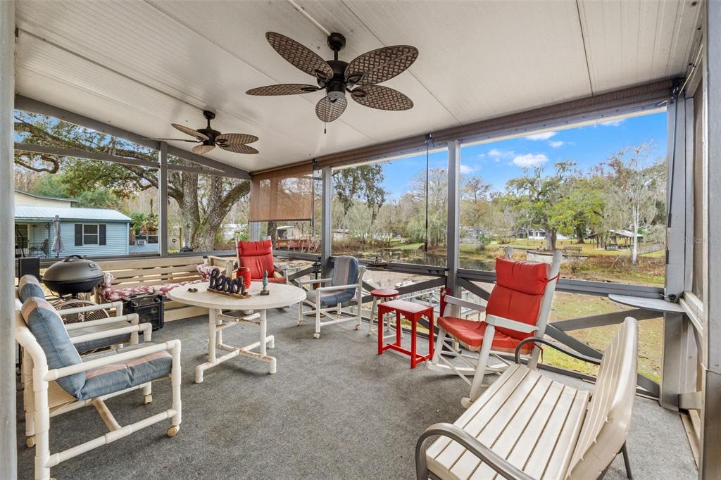 A screened-in porch features outdoor furniture, ceiling fans, and a view of a grassy yard — 7154 CO RD 651, BUSHNELL, FL