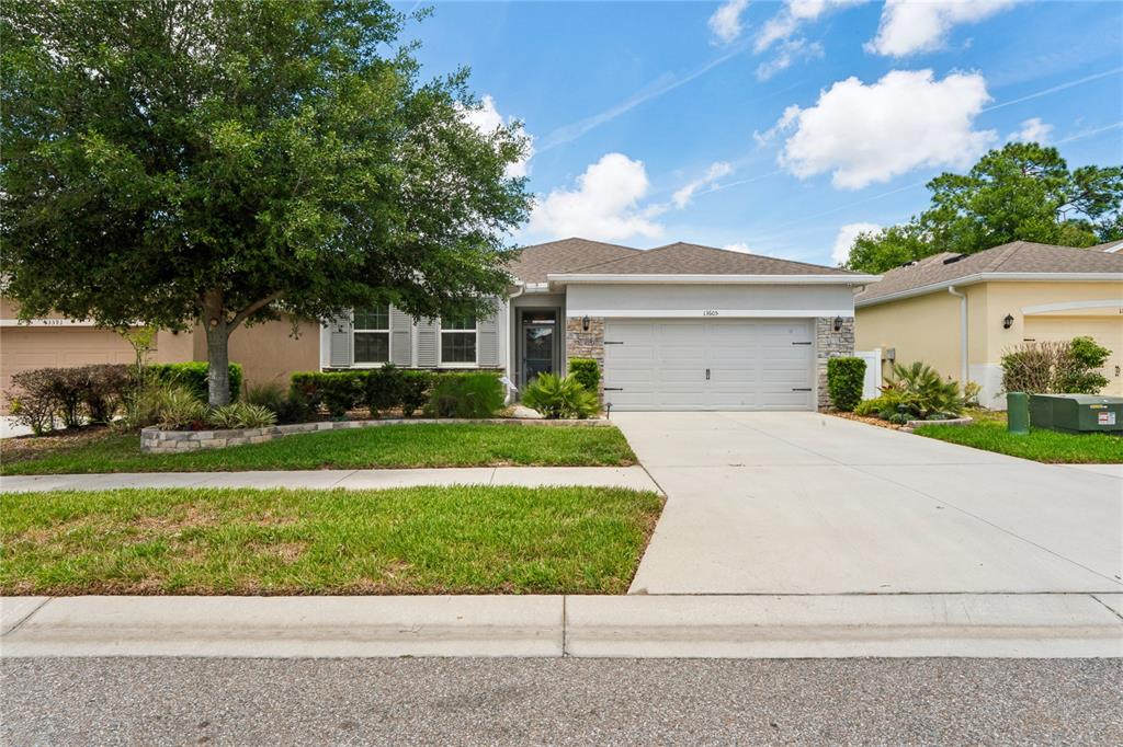 A hallway with light walls, a round nautical rug, and a view into the living area — 13605 PADDINGTON WAY, SPRING HILL, FL