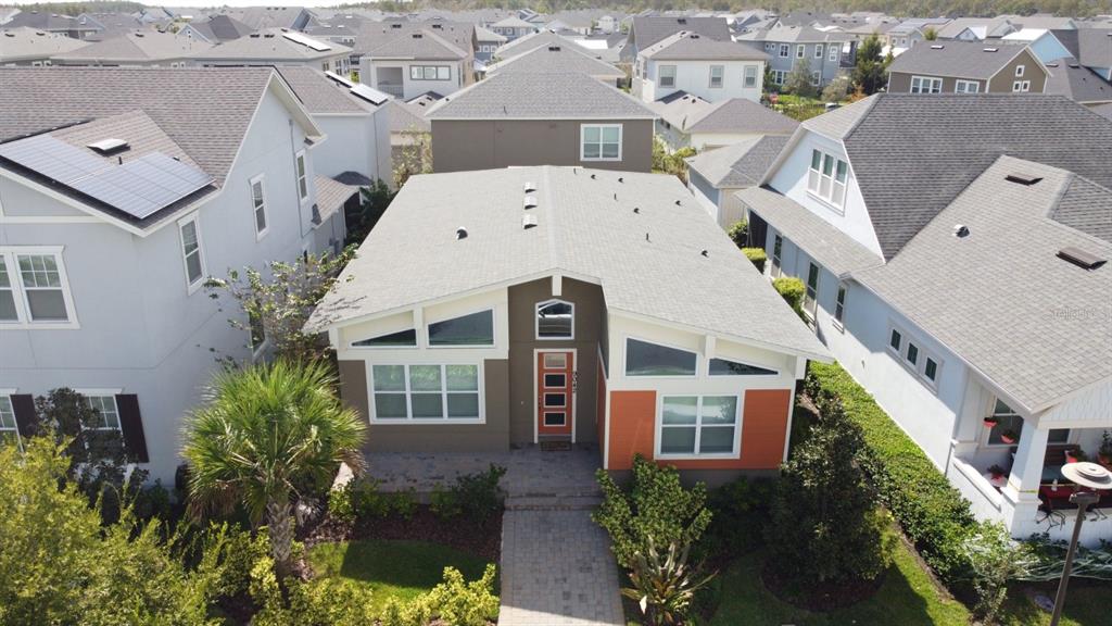 An aerial view of a modern suburban house with a distinctive orange front door — 9042 YONATH STREET, ORLANDO, FL