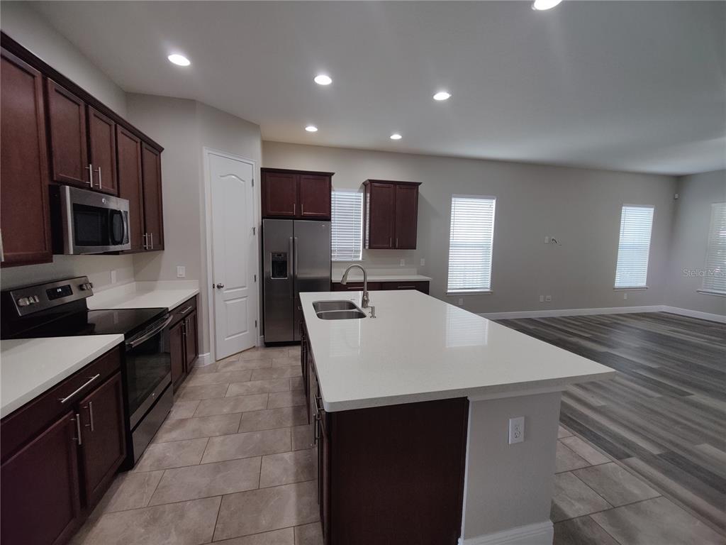 A kitchen with dark wood cabinets, a white quartz island, and tile flooring — 9042 YONATH STREET, ORLANDO, FL