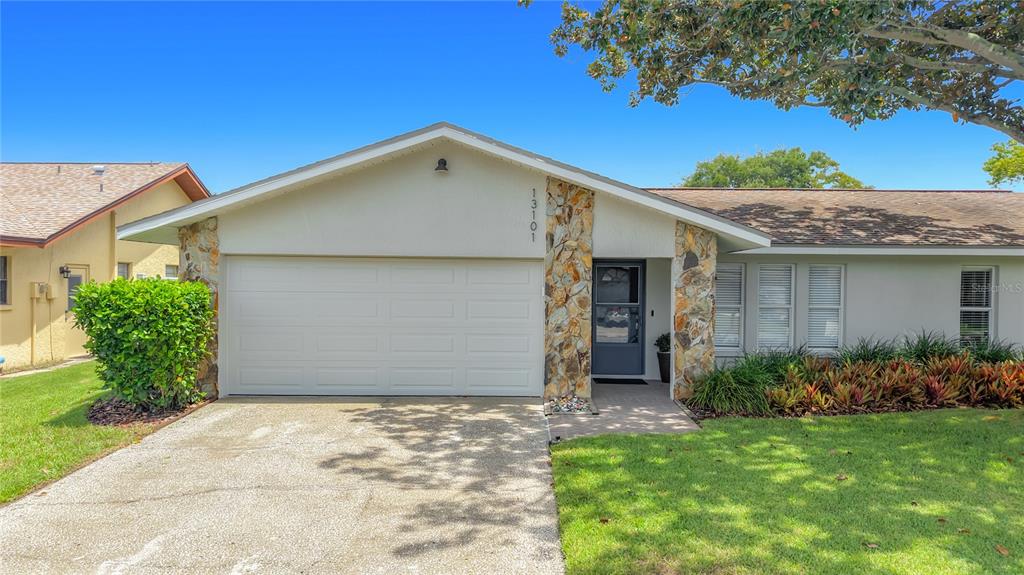 A single-story house features a white garage, stone accents, and a front lawn — 13101 116TH STREET, LARGO, FL