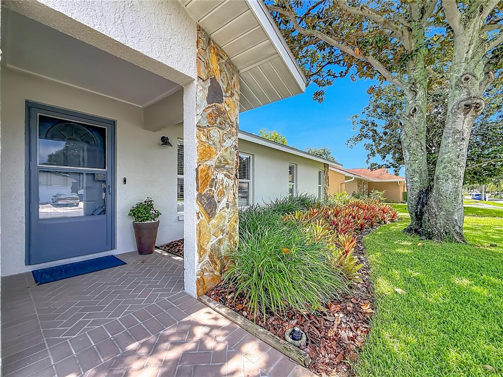 A house exterior features a stone-accented pillar, a covered entryway, and a landscaped front yard — 13101 116TH STREET, LARGO, FL