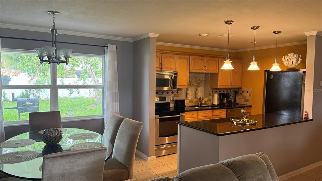 A dining area with a glass table sits adjacent to a kitchen with wood cabinets — 9652 COMMODORE DRIVE, SEMINOLE, FL
