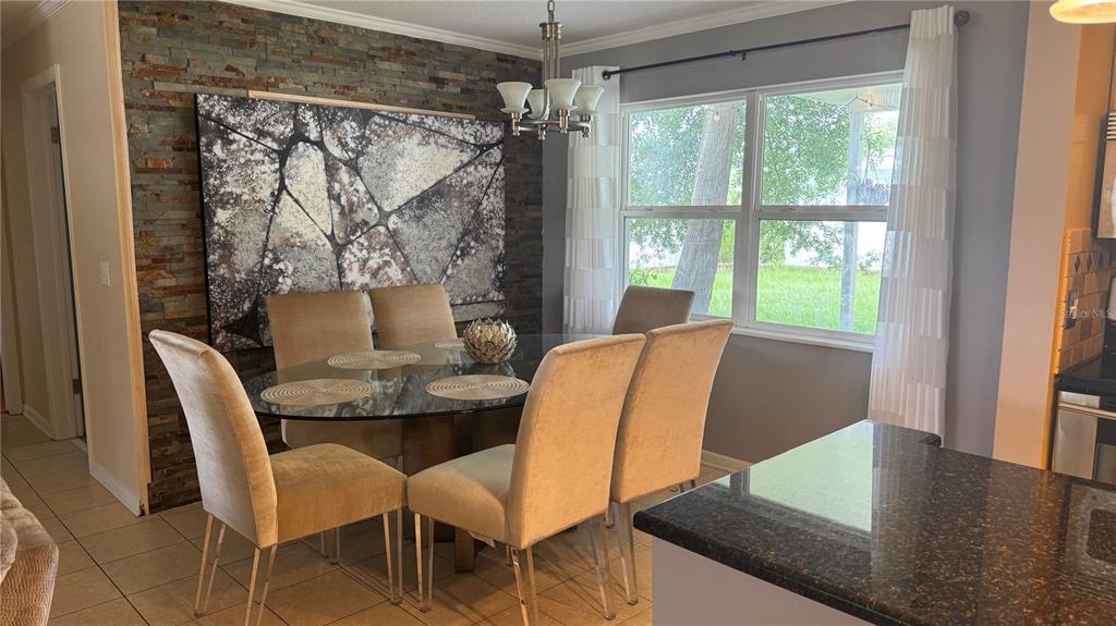 A dining area features a glass-topped table, upholstered chairs, and a stone accent wall — 9652 COMMODORE DRIVE, SEMINOLE, FL