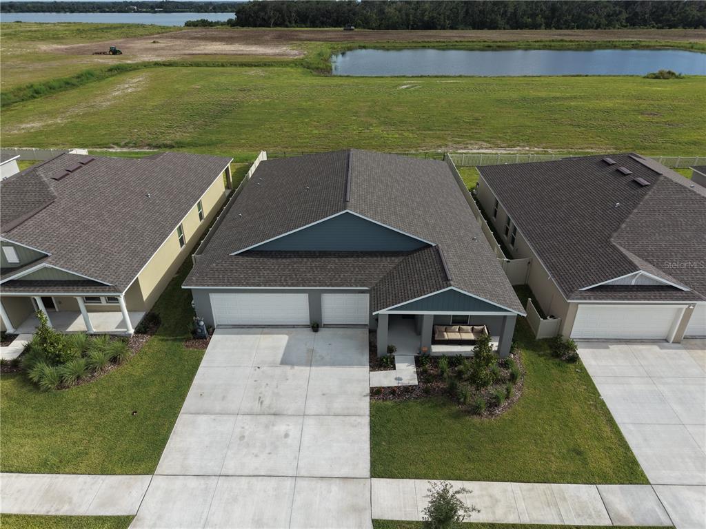 An aerial view shows a suburban house with a two-car garage and a front porch — 13421 NEW JADE AVENUE, WIMAUMA, FL