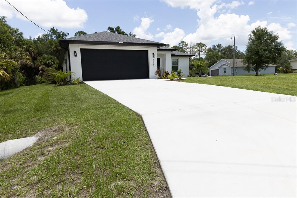 A single-story house with a white exterior, black garage door, and a concrete driveway — 4696 APRIL AVENUE, NORTH PORT, FL