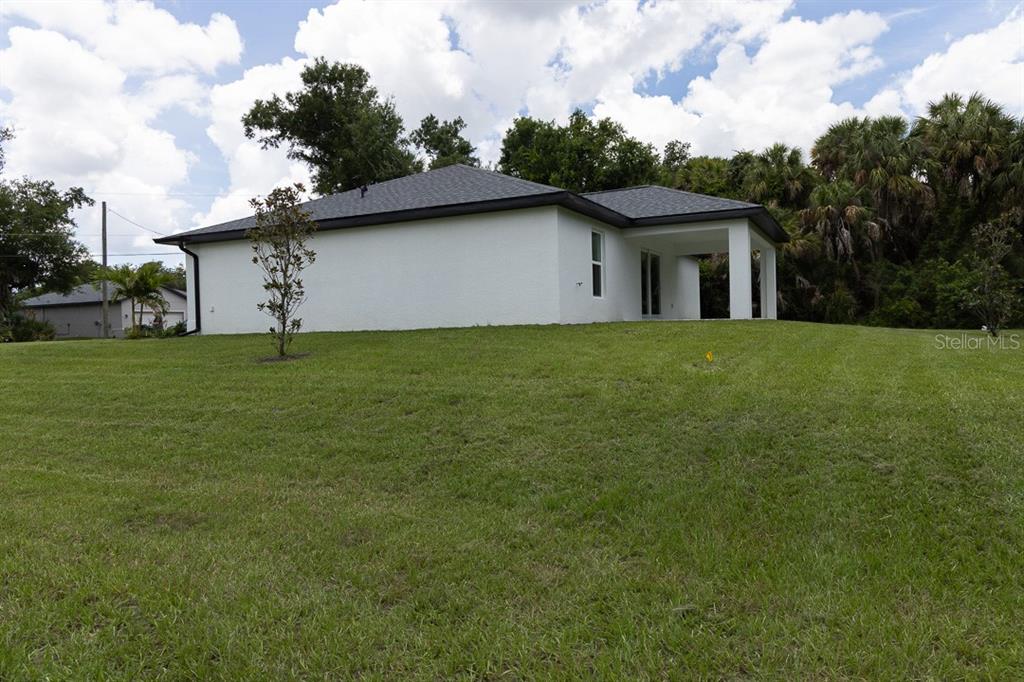 The exterior of a white, single-story house with a dark roof and a covered patio — 4696 APRIL AVENUE, NORTH PORT, FL
