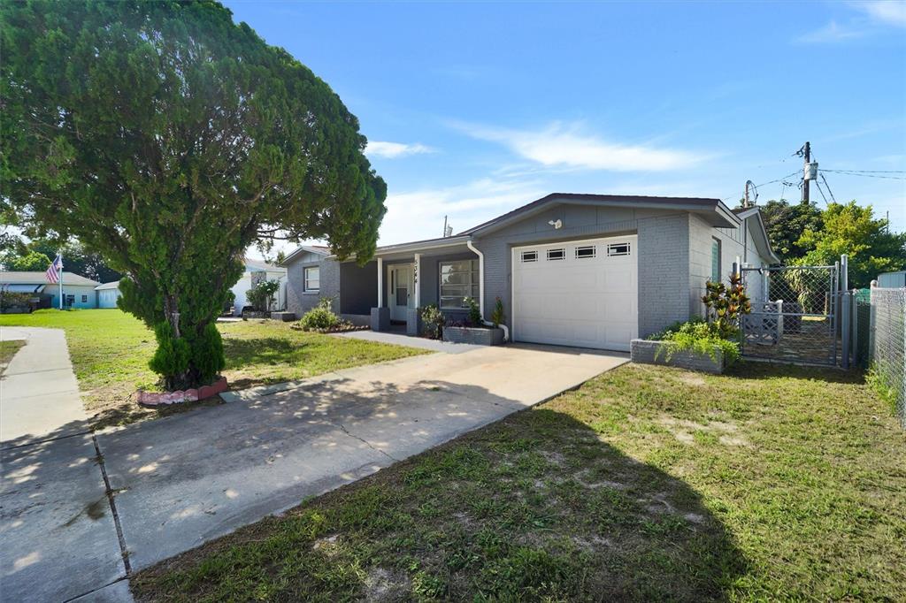 A covered porch features gray brick walls, two dark chairs, and a small matching table — 5344 NANCY LANE, HOLIDAY, FL