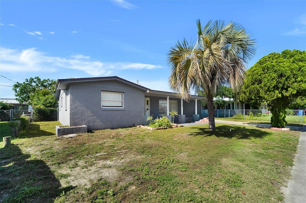 A gray brick house features a covered front porch with two chairs and a lawn — 5344 NANCY LANE, HOLIDAY, FL