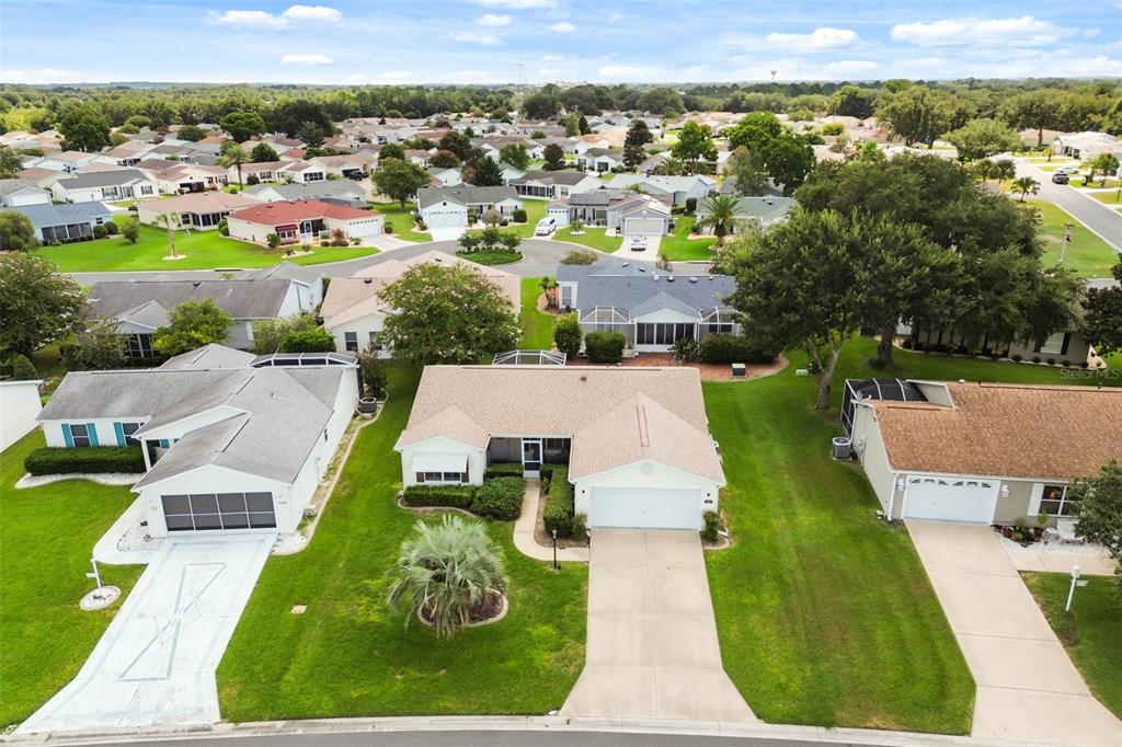 An aerial view shows a suburban neighborhood with single-family homes, manicured lawns, and paved driveways — 2527 BOTELLO AVENUE, THE VILLAGES, FL