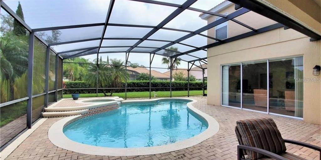 A screened-in patio features a swimming pool, a raised spa, and brick paver flooring — 10914 LEDGEMENT LANE, WINDERMERE, FL