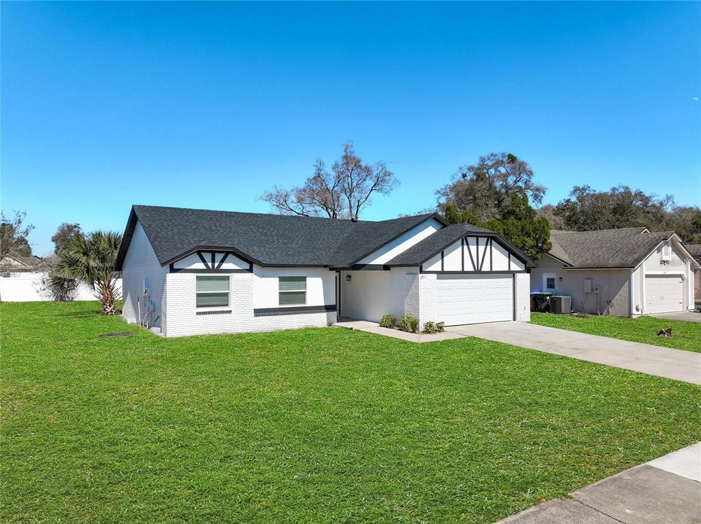A single-story white brick house with a dark roof and a two-car garage — 6911 CRESCENT RIDGE ROAD, ORLANDO, FL