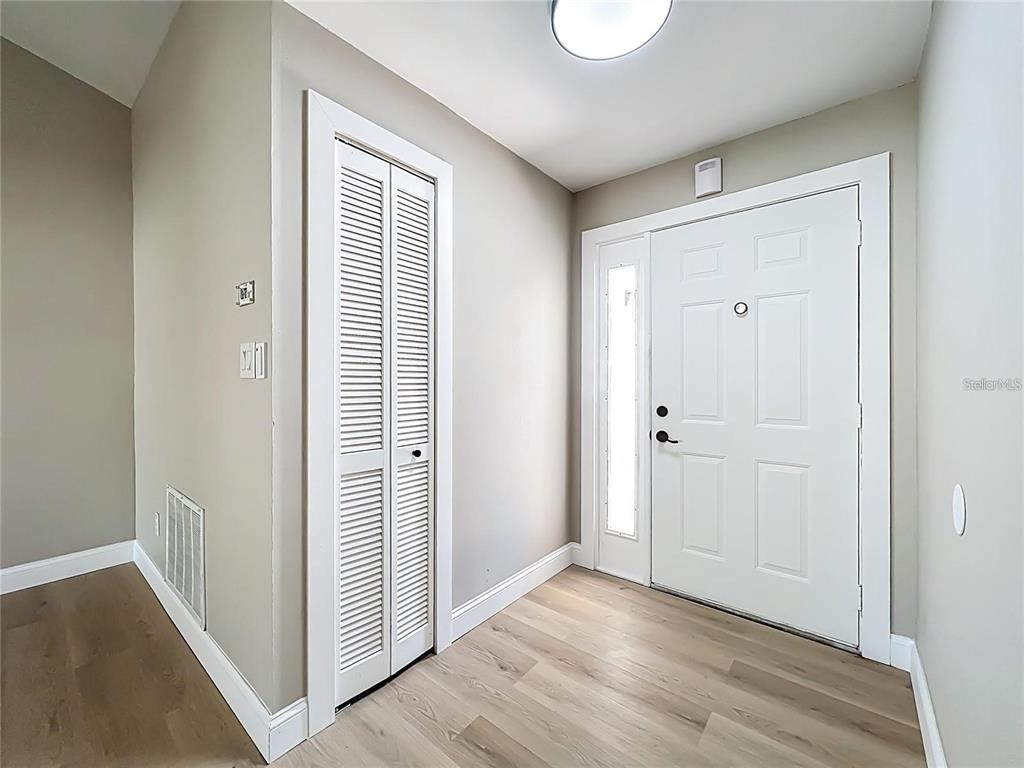 An entryway features light wood-look flooring, a white front door with a sidelight, and a closet — 6911 CRESCENT RIDGE ROAD, ORLANDO, FL