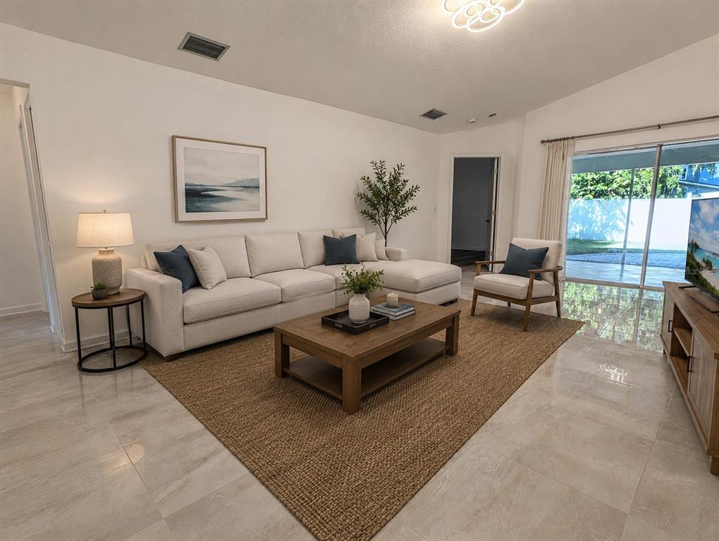 A living room features a beige sectional sofa, a wooden coffee table, and tile flooring — 4557 WORCESTER ROAD, SARASOTA, FL
