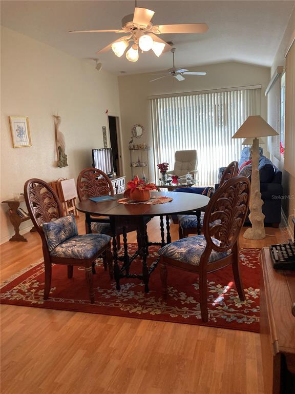 A dining area features a round wooden table, four carved chairs, and a red rug — 1275 BERKSHIRE CIRCLE, VENICE, FL