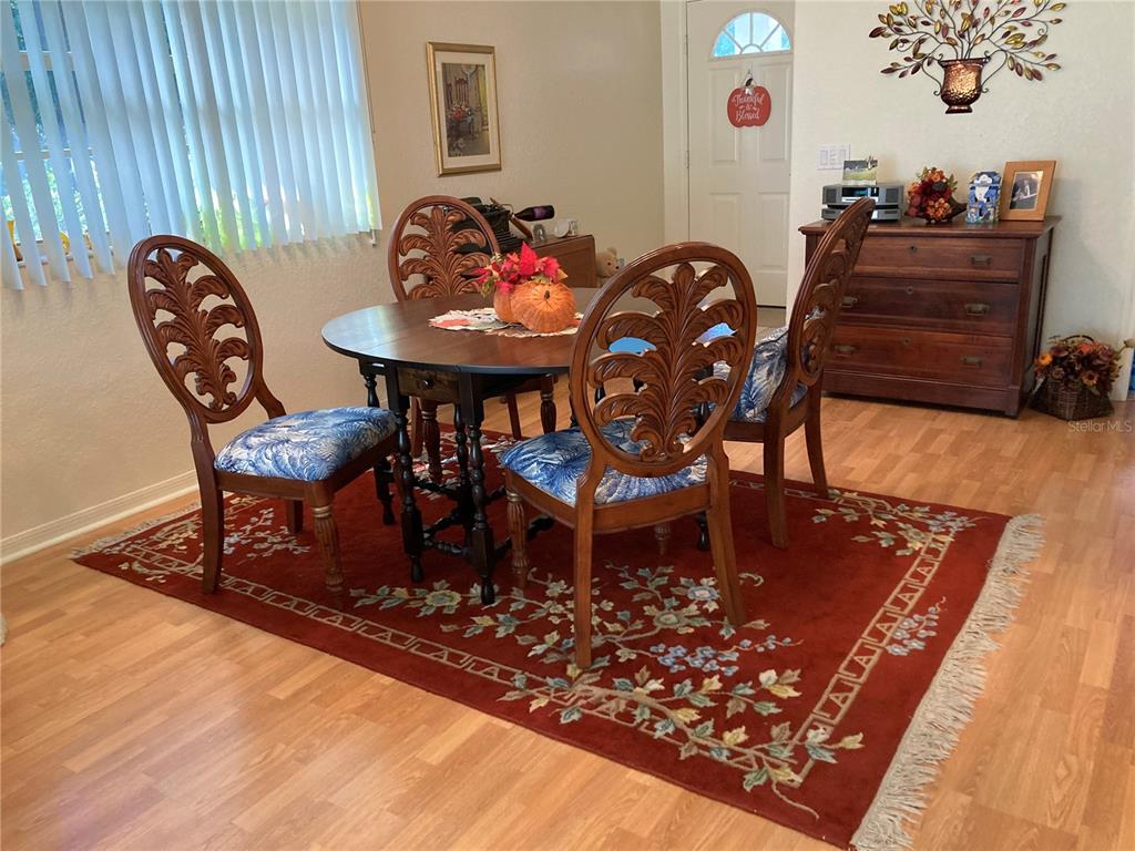 A dining room features a round wooden table, four carved chairs, and a patterned rug — 1275 BERKSHIRE CIRCLE, VENICE, FL