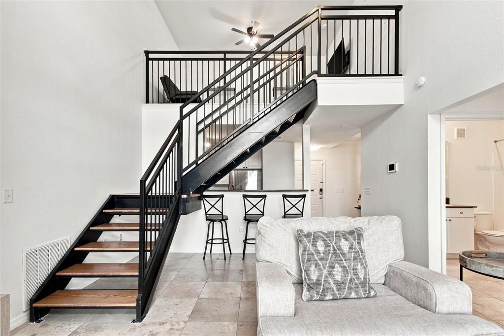 A living area features a staircase leading to a loft, tile flooring, and bar seating — 4221 W SPRUCE STREET UNIT 2425, TAMPA, FL