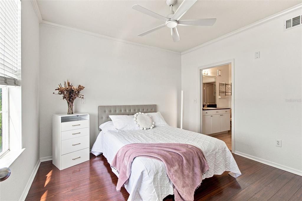 A bedroom features a bed with a pink throw, a white dresser, and an attached bathroom — 4221 W SPRUCE STREET UNIT 2425, TAMPA, FL