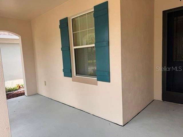 A covered porch with a window featuring teal shutters and a dark front door — 6803 LOCKINGTON COURT, TAMPA, FL