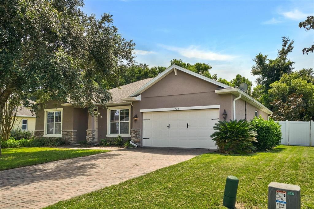 A single-story house with a beige stucco exterior, stone accents, and a paved driveway — 1720 LADY FERN TRAIL, DELAND, FL