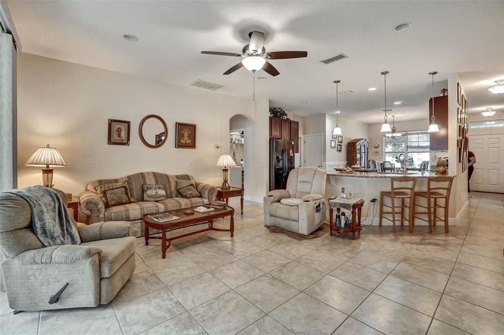 A living room with tile floors, a sofa, two recliners, and an open kitchen beyond — 1720 LADY FERN TRAIL, DELAND, FL