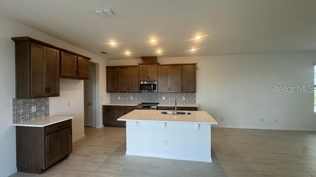 A kitchen with brown cabinets, a white island, and light-colored flooring — 416 OAK FLAT ALLEY, GROVELAND, FL
