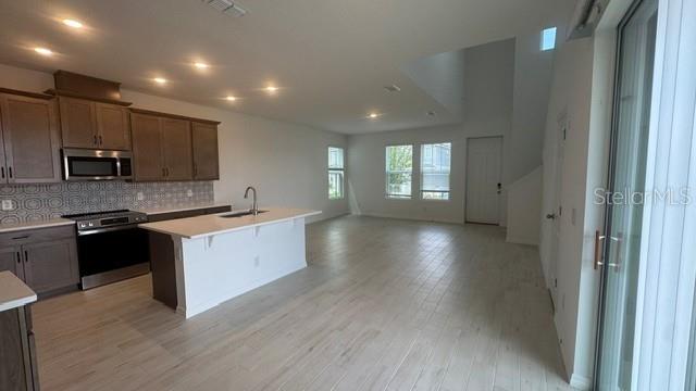 A kitchen with a center island and light wood-look tile floors opens to a living area — 416 OAK FLAT ALLEY, GROVELAND, FL