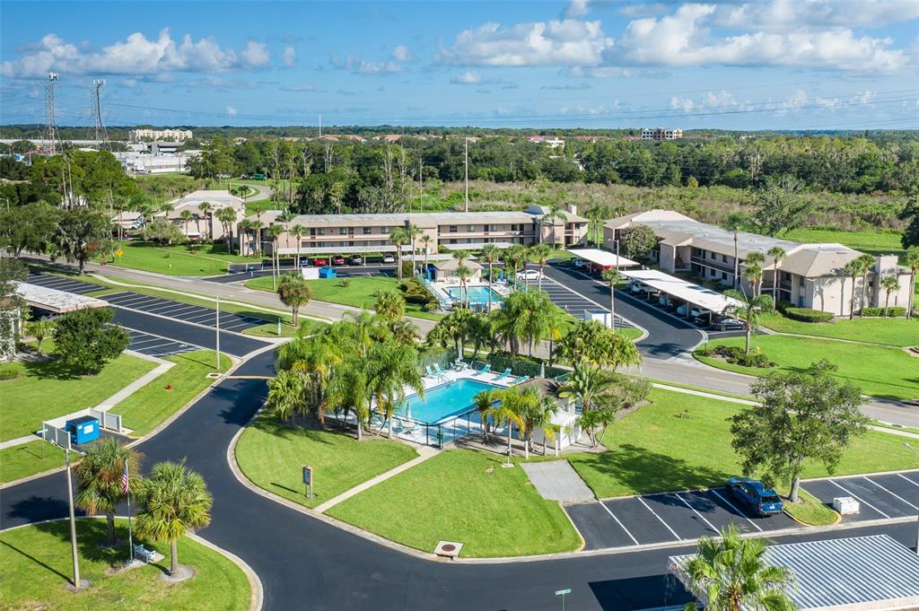 An aerial view shows a multi-story apartment complex with two swimming pools and parking lots — 160 LAKEVIEW WAY UNIT 160, OLDSMAR, FL