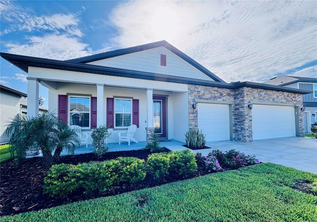 A single-story house with a stone facade, two garage doors, and a covered front porch — 11753 JUNE BRIAR LOOP, SAN ANTONIO, FL