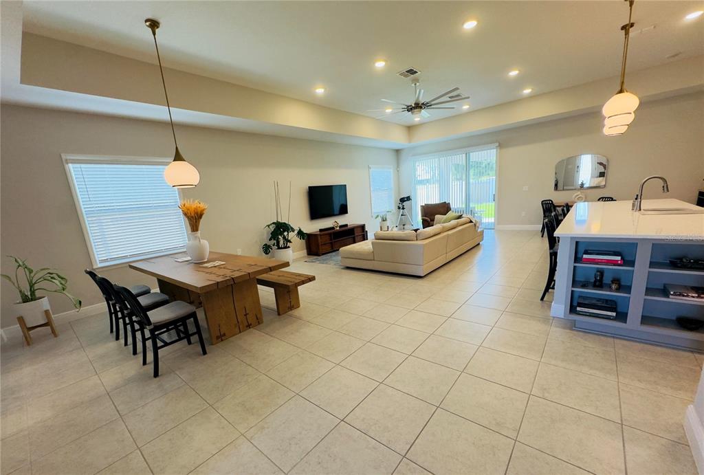 An open-concept living and dining area features tile flooring, a wooden table, and a kitchen island — 11753 JUNE BRIAR LOOP, SAN ANTONIO, FL