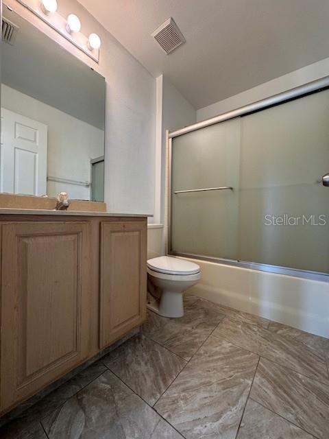 A bathroom features a wooden vanity, a toilet, and a shower with sliding glass doors — 2405 LINCOLNSHIRE COURT, KISSIMMEE, FL