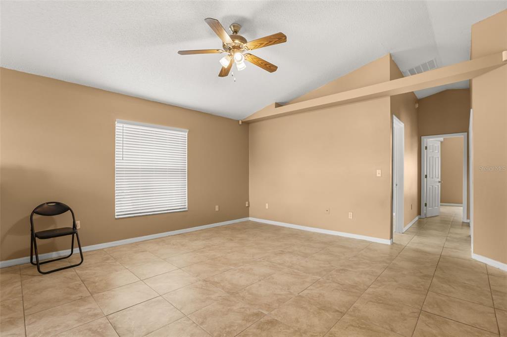 An empty room with tan walls, tile flooring, a ceiling fan, and a folding chair — 2501 DAFFADIL TERRACE, SANFORD, FL