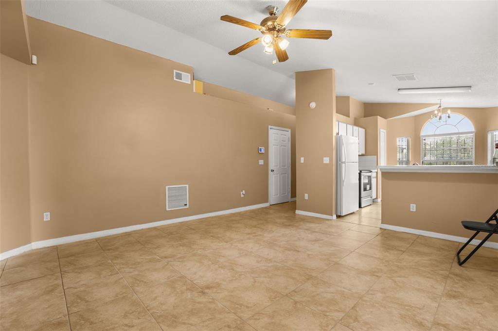 An open-concept living area features tan walls, tile flooring, a ceiling fan, and a kitchen — 2501 DAFFADIL TERRACE, SANFORD, FL
