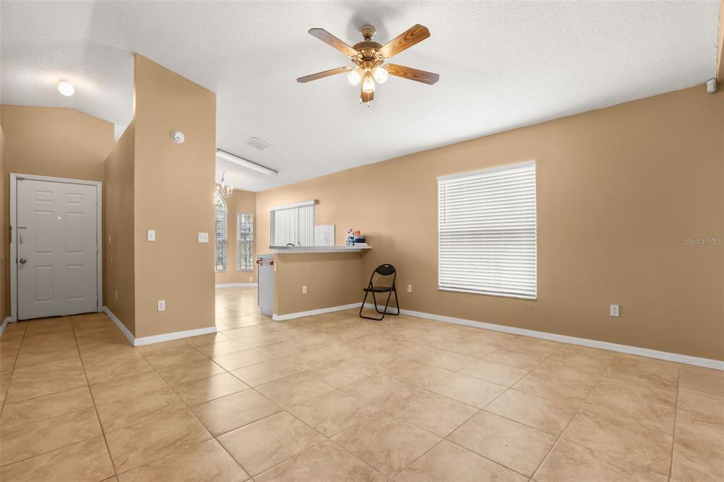 A living room with tan walls, tile flooring, a ceiling fan, and a breakfast bar — 2501 DAFFADIL TERRACE, SANFORD, FL