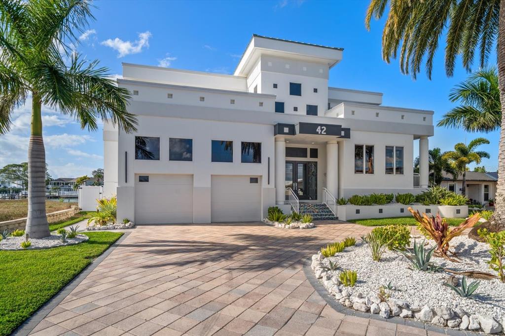 A modern two-story house with a paved driveway, a two-car garage, and palm trees — 42 MIDWAY ISLAND, CLEARWATER BEACH, FL