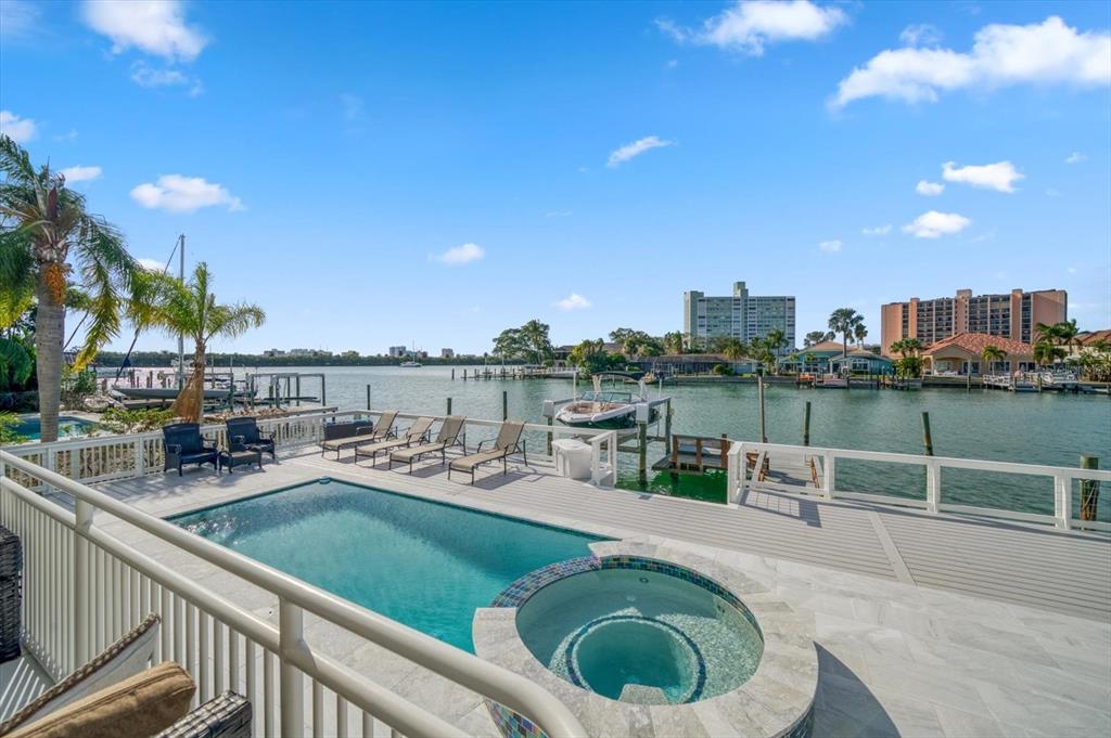 An outdoor deck features a swimming pool, a hot tub, and a view of water — 42 MIDWAY ISLAND, CLEARWATER BEACH, FL
