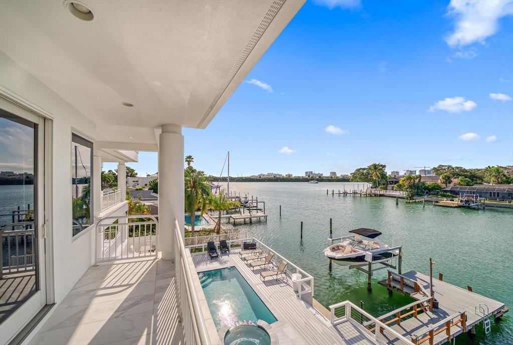 A balcony overlooks a swimming pool, a private dock, and a waterway with boats — 42 MIDWAY ISLAND, CLEARWATER BEACH, FL