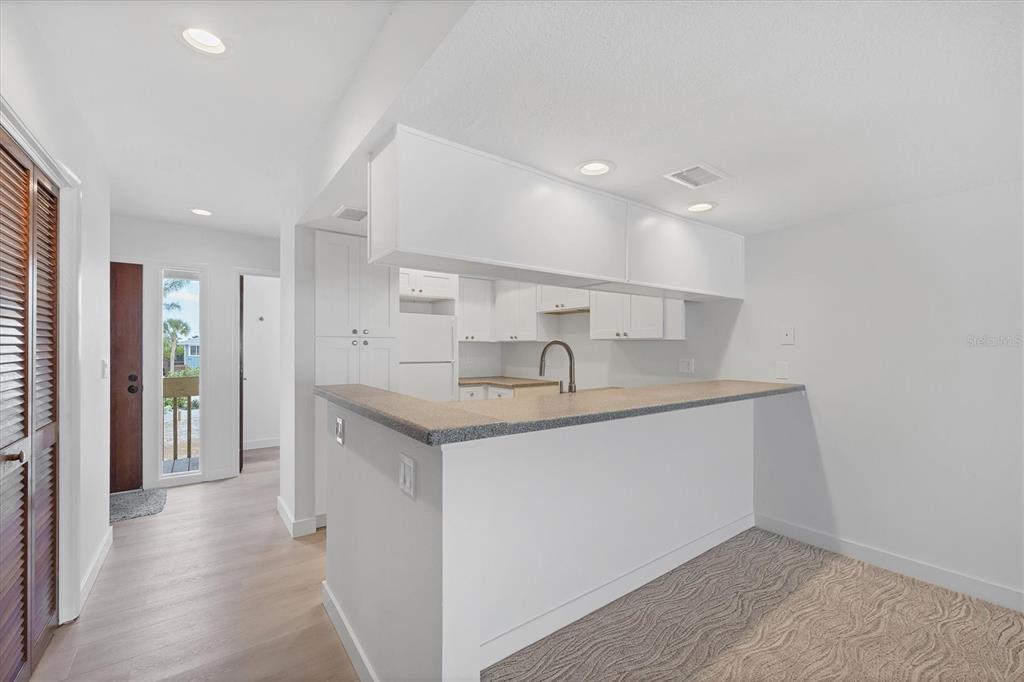 A kitchen with white cabinets and a breakfast bar overlooks a carpeted living area — 301 S GULF BOULEVARD UNIT 12, PLACIDA, FL