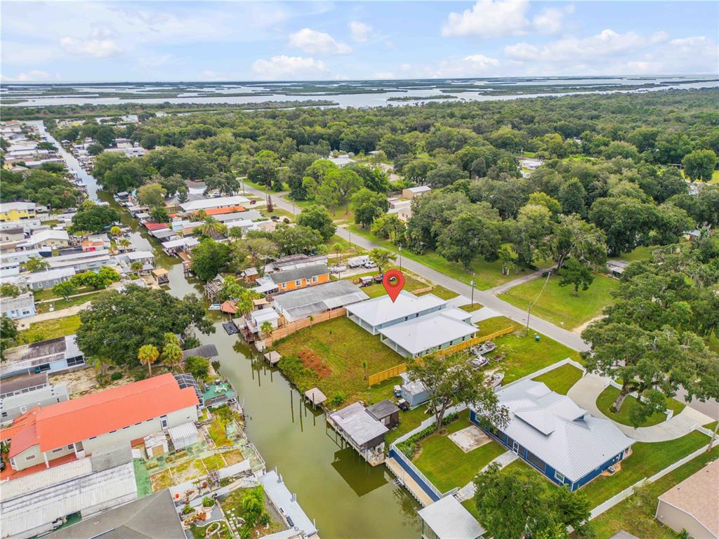 An aerial view shows a waterfront house with a metal roof and a canal — 128 INDIAN CREEK ROAD, OAK HILL, FL