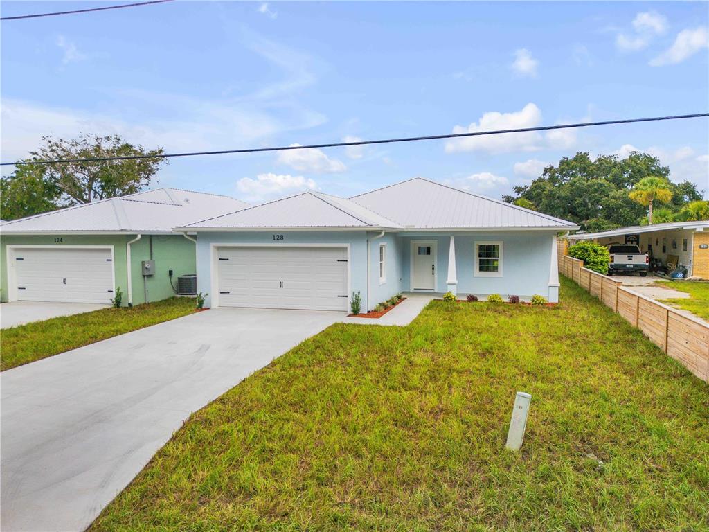A light blue single-story house with a white garage door and a metal roof — 128 INDIAN CREEK ROAD, OAK HILL, FL