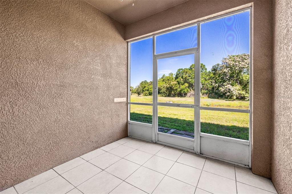 A screened-in patio with light-colored tile flooring and a view of a grassy backyard — 10418 TULIP FIELD WAY, RIVERVIEW, FL