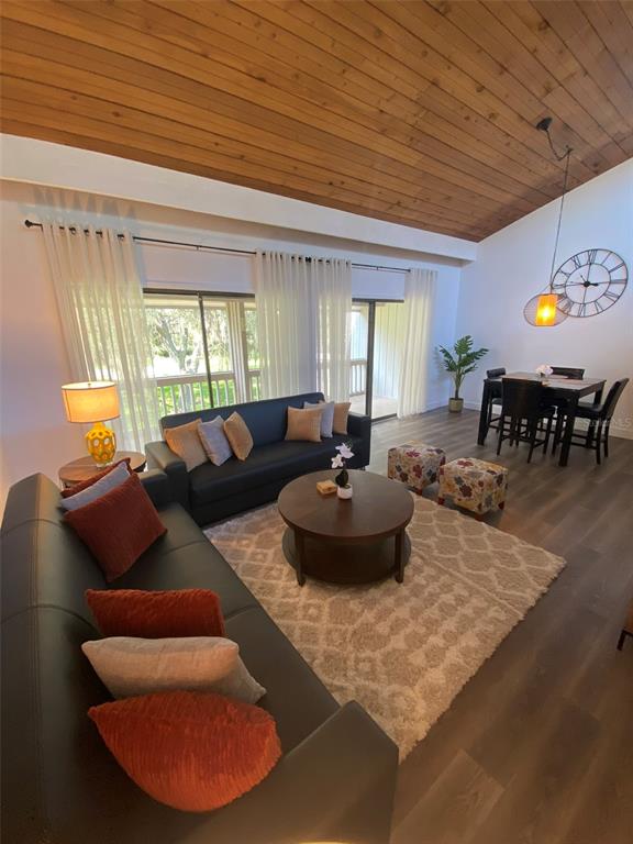 A living room features a vaulted wood ceiling, two dark sofas, and a dining area — 507 MAPLE LEAF COURT UNIT N/A, HAINES CITY, FL