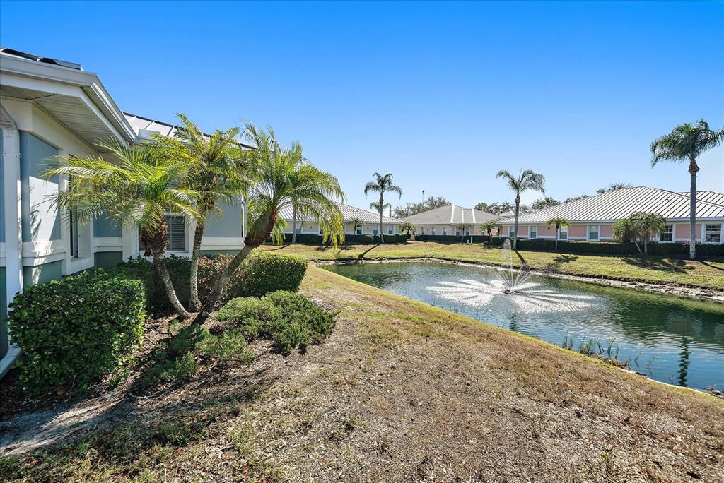 A pond with a fountain sits between a residential building and landscaped grounds — 5605 MARQUESAS CIRCLE UNIT 12C, SARASOTA, FL
