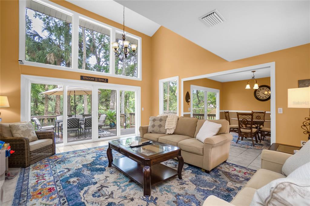 A living room with high ceilings, large windows, a beige sofa, and a patterned rug — 28 RIVERTRAIL DRIVE, INGLIS, FL