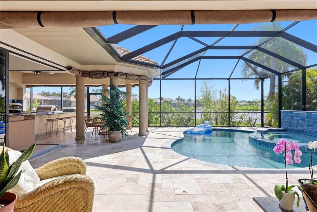 A covered patio with a pool, spa, and outdoor kitchen enclosed by a screen cage — 815 TROPEZ LANE, VENICE, FL