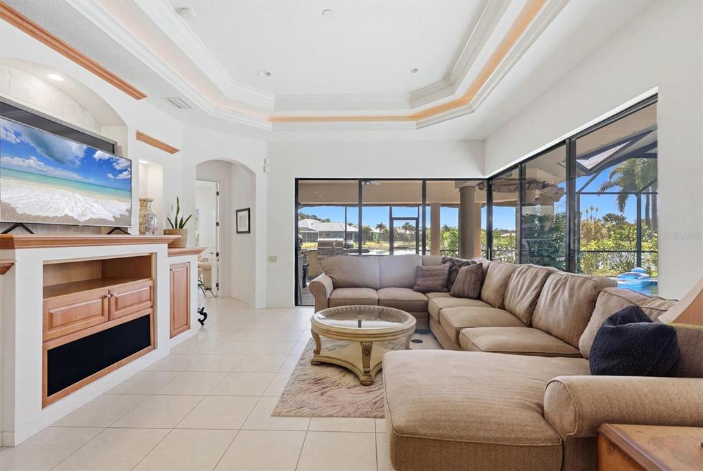 A living room features a tray ceiling, tile floors, a large sectional, and sliding glass doors — 815 TROPEZ LANE, VENICE, FL