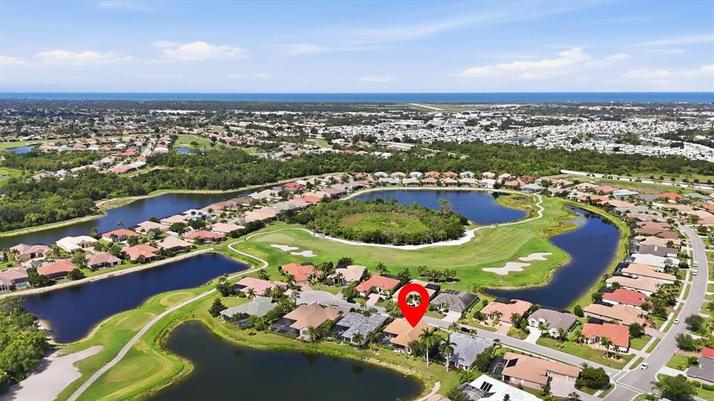 An aerial view shows a residential neighborhood with houses surrounding a golf course and lake — 815 TROPEZ LANE, VENICE, FL